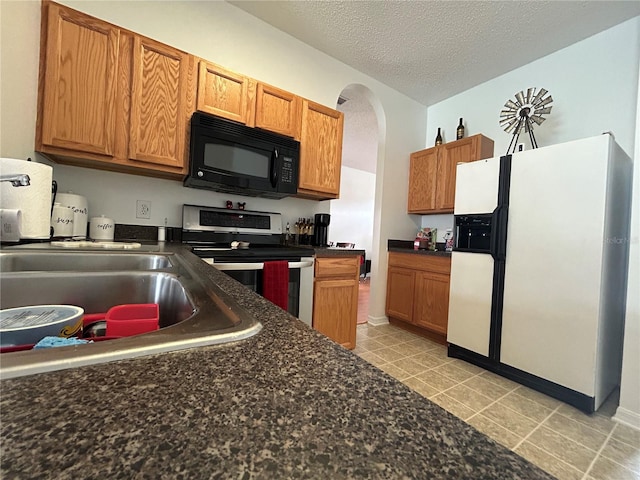 kitchen featuring light tile patterned floors, a textured ceiling, white fridge with ice dispenser, sink, and stainless steel range with electric cooktop