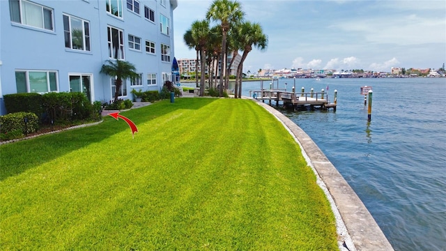 view of dock with a water view and a yard