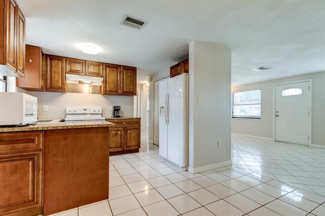 kitchen with white appliances, light stone countertops, light tile patterned flooring, and decorative backsplash