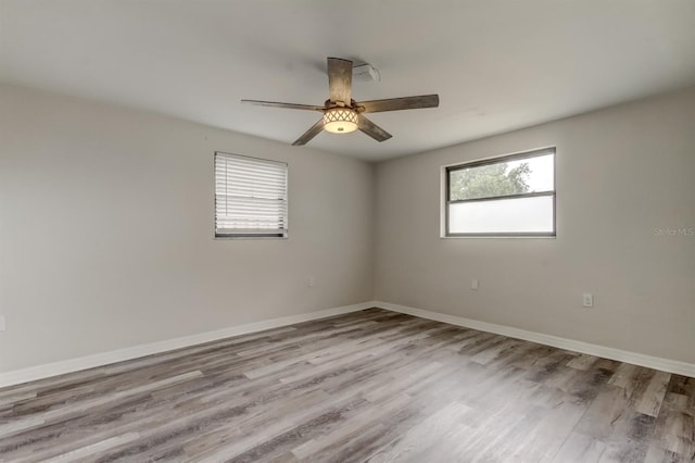 empty room with a wealth of natural light, ceiling fan, and light hardwood / wood-style floors