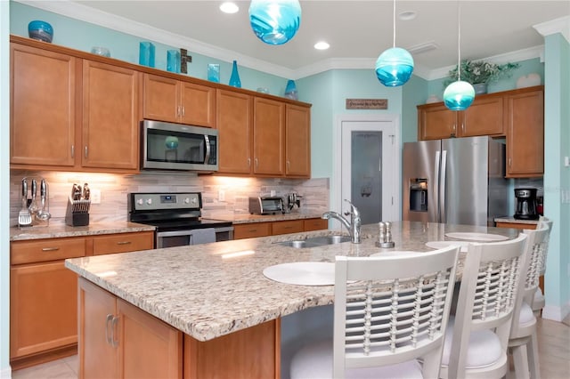 kitchen featuring an island with sink, stainless steel appliances, decorative light fixtures, ornamental molding, and sink