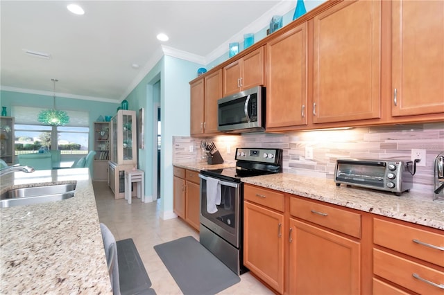 kitchen featuring light stone counters, pendant lighting, sink, appliances with stainless steel finishes, and crown molding