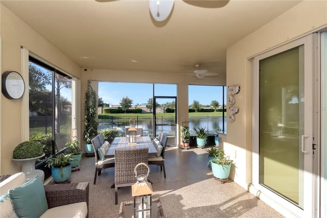 sunroom featuring ceiling fan and a water view