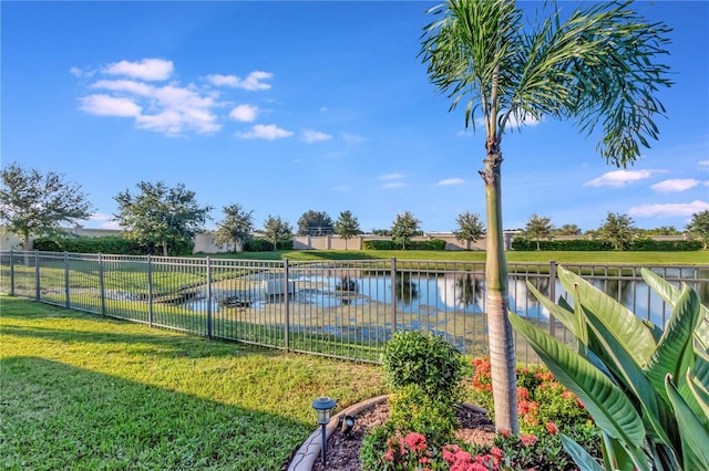 view of pool with a lawn and a water view