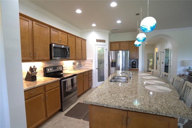 6342 Kenava Loop, Palmetto, FL 34221 - kitchen featuring appliances with stainless steel finishes, a large island, brown cabinetry, crown molding, and backsplash