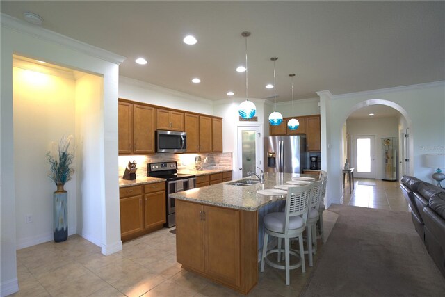 6342 Kenava Loop, Palmetto, FL 34221 - kitchen with stainless steel appliances, brown cabinetry, arched walkways, backsplash, and light tile patterned floors