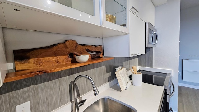 kitchen with dark hardwood / wood-style flooring, sink, range, white cabinetry, and butcher block counters