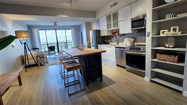 kitchen featuring appliances with stainless steel finishes, light hardwood / wood-style flooring, white cabinetry, and ceiling fan