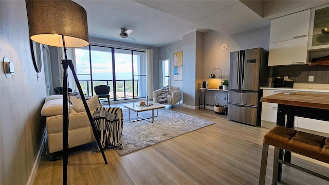 living room with ceiling fan, light hardwood / wood-style floors, and a textured ceiling