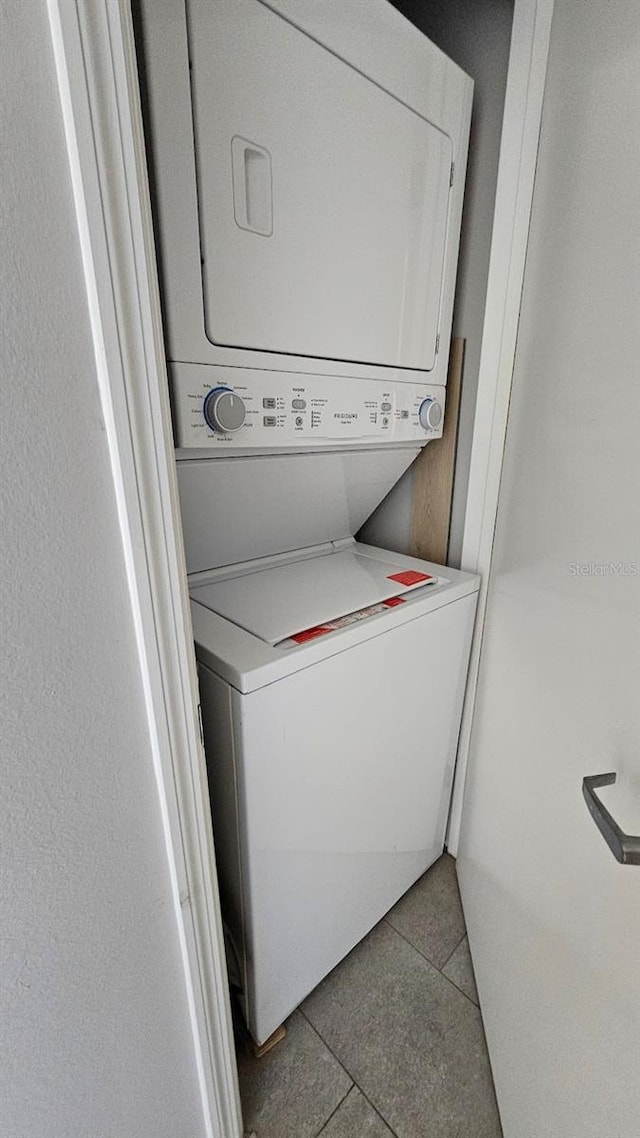 clothes washing area with light tile patterned floors and stacked washer and dryer