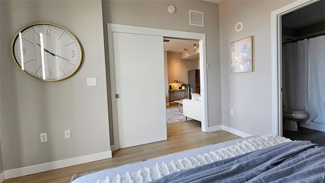 bedroom featuring hardwood / wood-style flooring and ensuite bathroom