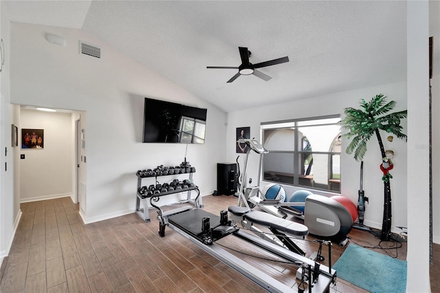 exercise area featuring lofted ceiling, ceiling fan, hardwood / wood-style floors, and a textured ceiling