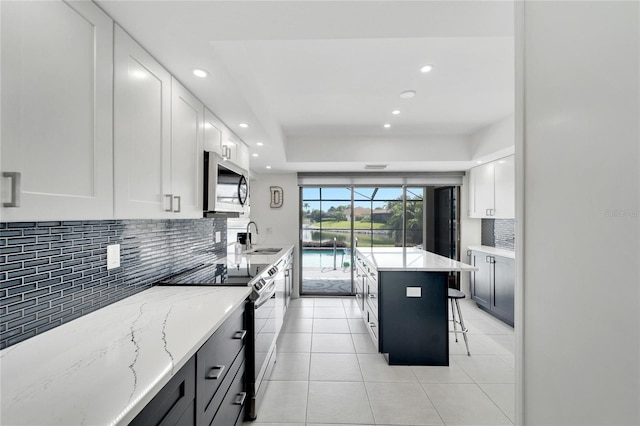 kitchen with light stone counters, sink, white cabinetry, appliances with stainless steel finishes, and a kitchen breakfast bar