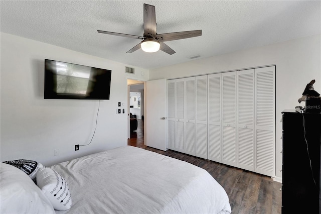 bedroom with ceiling fan, a textured ceiling, a closet, and dark wood-type flooring