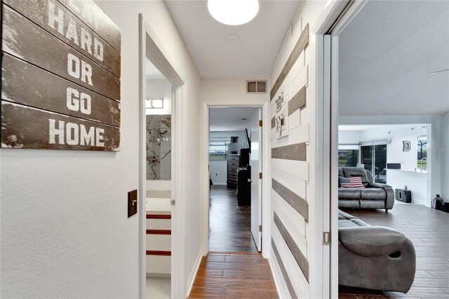 hallway with a textured ceiling and dark wood-type flooring