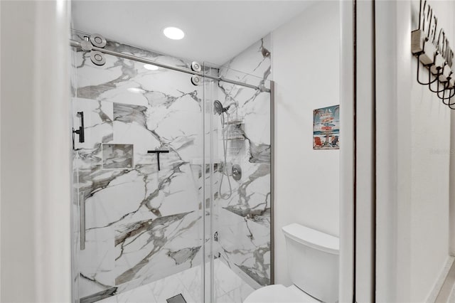 bathroom featuring a shower with door and toilet