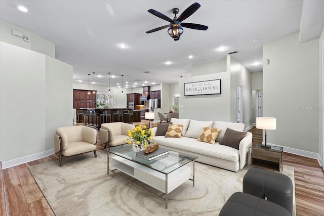 living room with light hardwood / wood-style flooring and ceiling fan