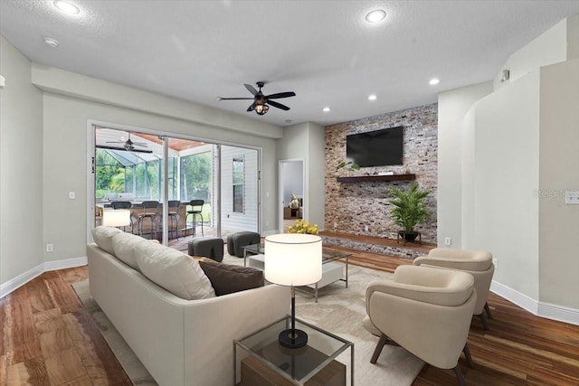 living room with hardwood / wood-style floors, ceiling fan, and a textured ceiling