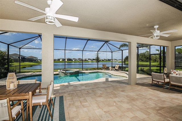 view of pool with an in ground hot tub, a water view, a patio area, glass enclosure, and ceiling fan