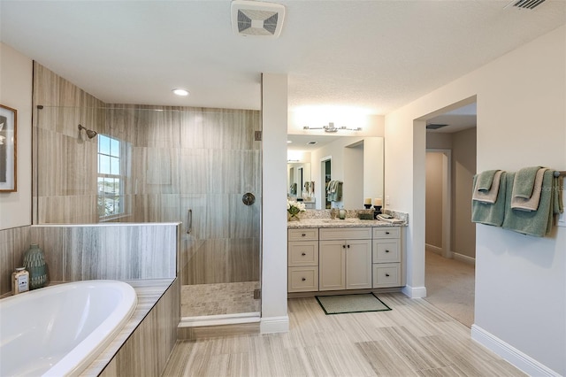 bathroom with vanity, independent shower and bath, a textured ceiling, and hardwood / wood-style floors