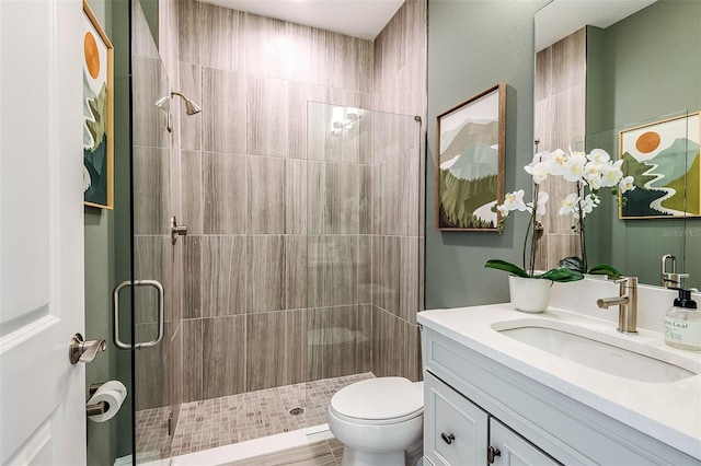 bathroom with vanity, a shower with shower door, and toilet