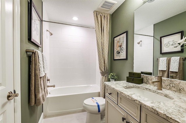 full bathroom featuring vanity, toilet, tiled shower / bath combo, and a textured ceiling