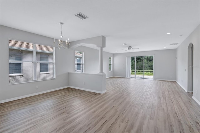 unfurnished living room with ceiling fan with notable chandelier, light hardwood / wood-style flooring, and ornate columns