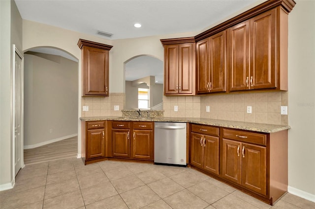 kitchen with tasteful backsplash, dishwasher, sink, light tile patterned floors, and light stone countertops