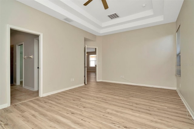 unfurnished bedroom featuring a tray ceiling, light hardwood / wood-style floors, and ceiling fan