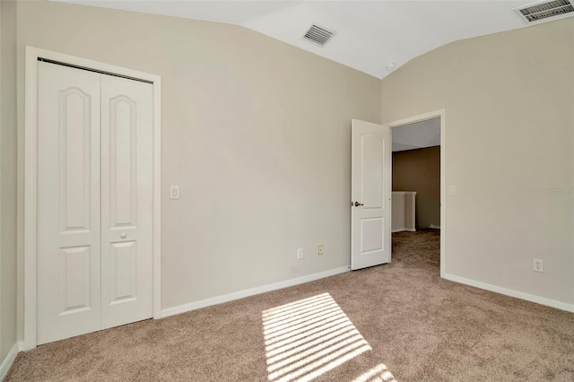 unfurnished bedroom featuring lofted ceiling, light carpet, and a closet