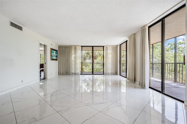 empty room with floor to ceiling windows and a textured ceiling