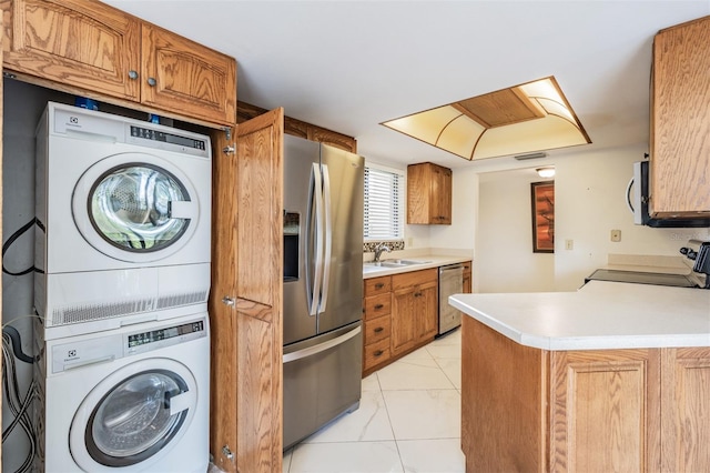 kitchen with stacked washer and dryer, kitchen peninsula, sink, and appliances with stainless steel finishes