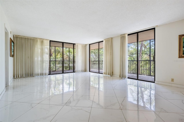 unfurnished room featuring a textured ceiling and floor to ceiling windows