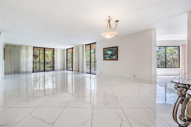 unfurnished room featuring floor to ceiling windows, a wealth of natural light, and a textured ceiling