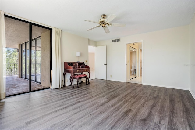 unfurnished room with light wood-type flooring, a textured ceiling, ceiling fan, and a wall of windows