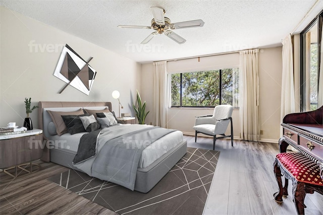 bedroom featuring a textured ceiling, dark hardwood / wood-style flooring, ceiling fan, and multiple windows