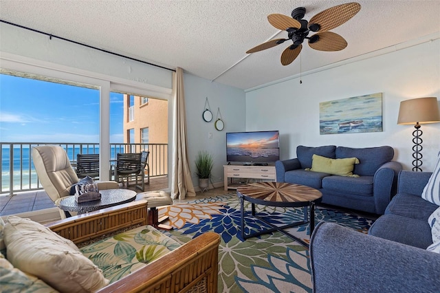 living room featuring a textured ceiling, ceiling fan, and a water view