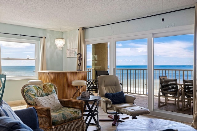 living area featuring a textured ceiling, a view of the beach, and a water view