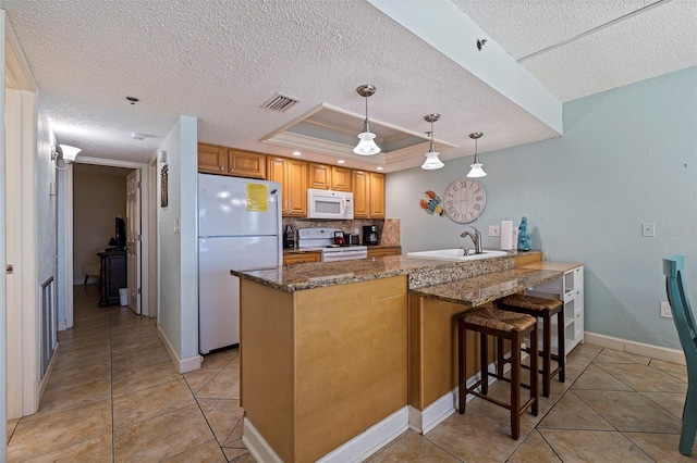 kitchen with a textured ceiling, white appliances, pendant lighting, a tray ceiling, and kitchen peninsula