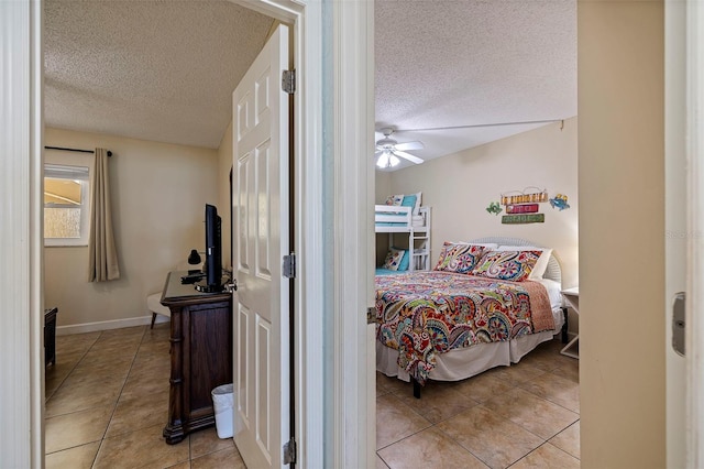 bedroom with a textured ceiling, ceiling fan, and light tile patterned flooring