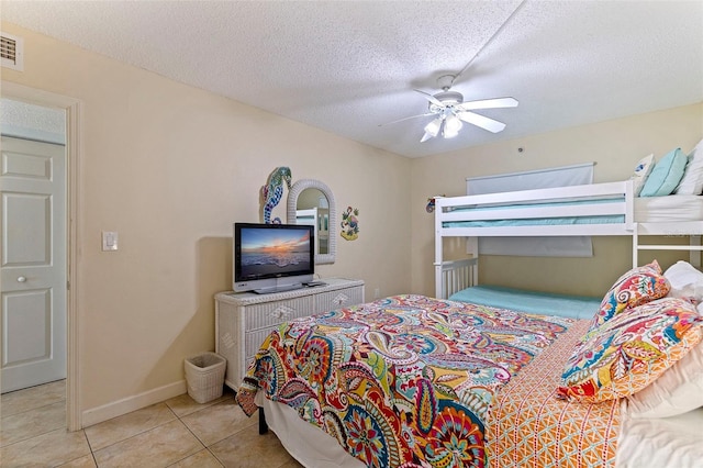 bedroom featuring ceiling fan, light tile patterned floors, and a textured ceiling