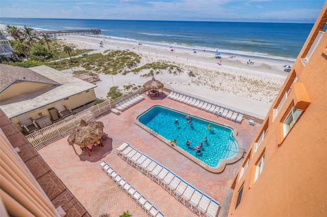 view of pool with a water view, a view of the beach, and a patio