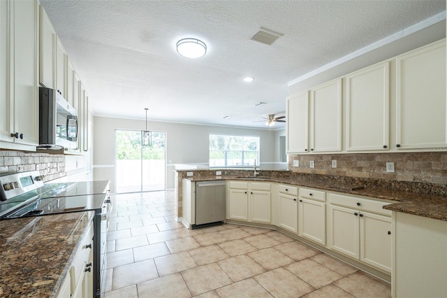 kitchen with dark stone counters, stainless steel appliances, decorative light fixtures, sink, and ceiling fan