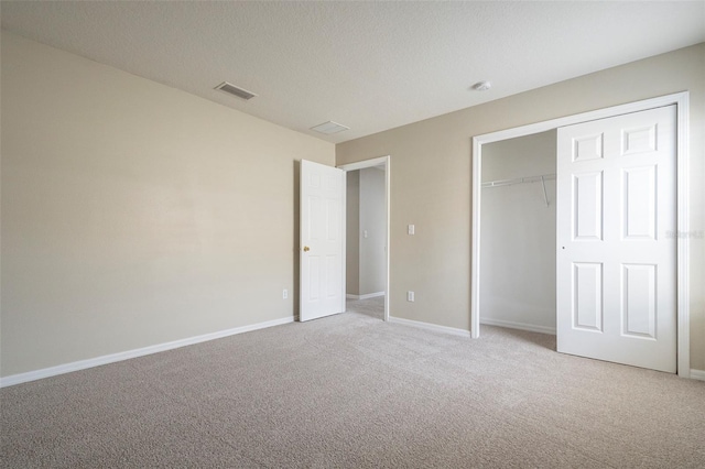 unfurnished bedroom featuring a textured ceiling, light colored carpet, and a closet