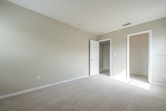 unfurnished bedroom with a closet, light carpet, and a spacious closet