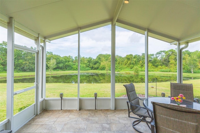 sunroom with lofted ceiling and a water view