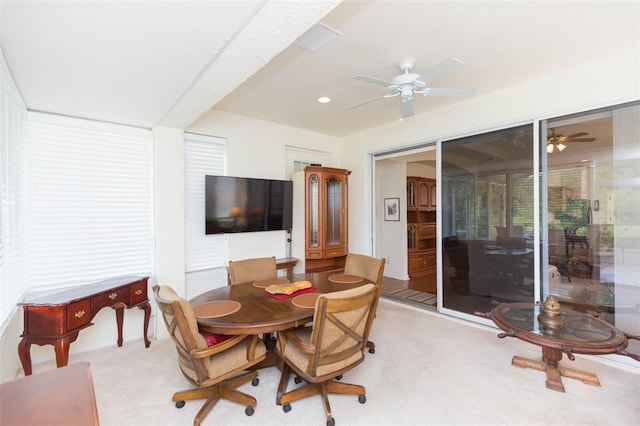 carpeted dining room with ceiling fan