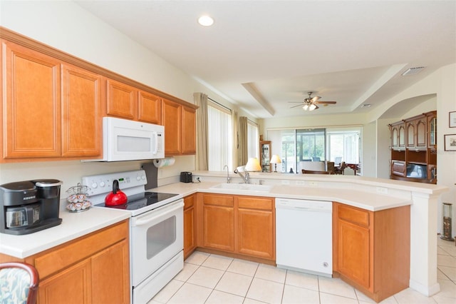 kitchen featuring ceiling fan, a raised ceiling, sink, kitchen peninsula, and white appliances