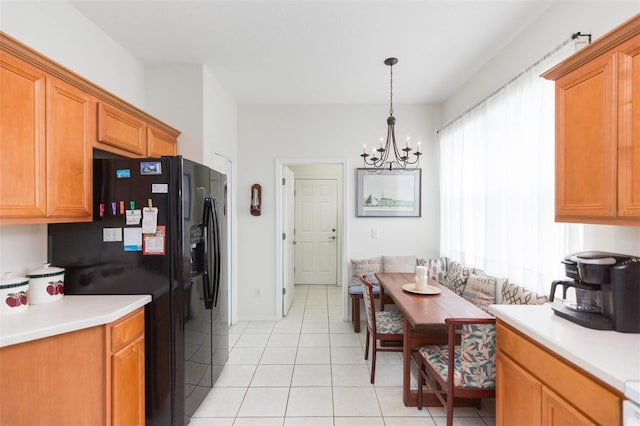 kitchen with light tile patterned floors, pendant lighting, black fridge, and a notable chandelier