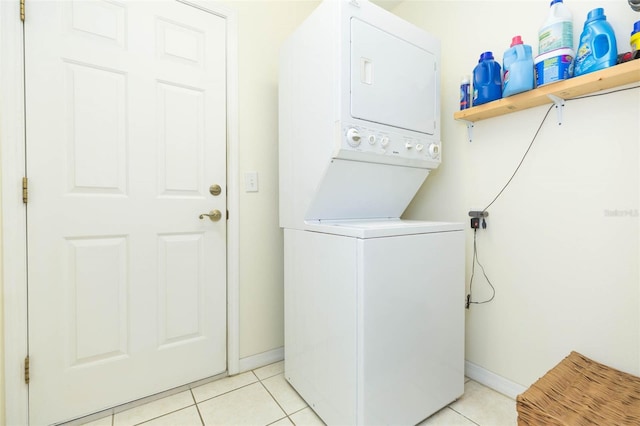 clothes washing area featuring light tile patterned flooring and stacked washer / drying machine